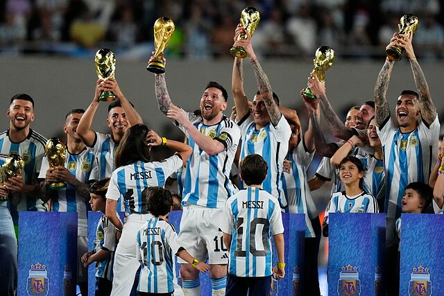 Lionel Messi raises the winning team replica of the FIFA World Cup trophy during a celebration ceremony.
