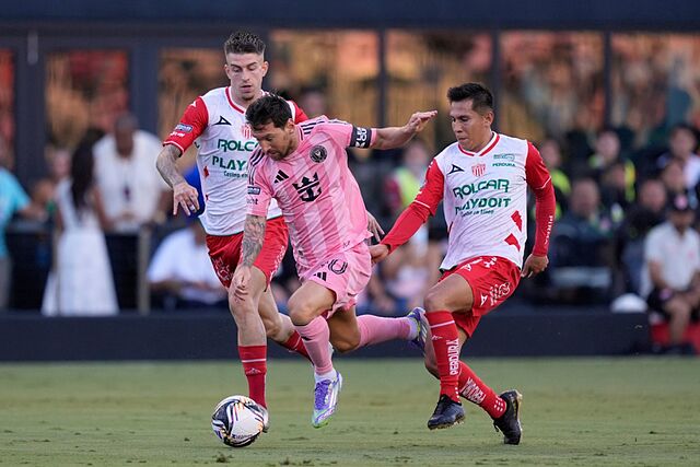 Inter Miami forward Lionel Messi, center, charges through Necaxa forward Raul Sanchez, left, and midfielder Jose Rodriguez